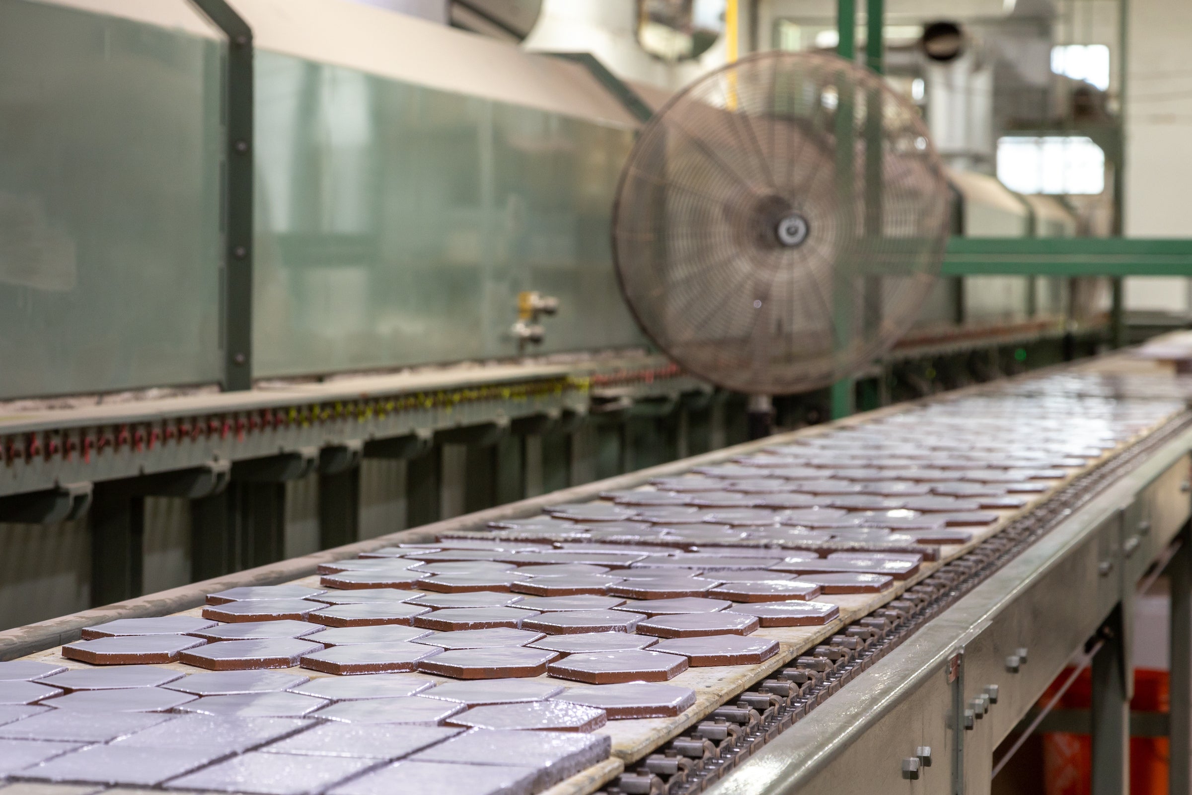 Rows of freshly glazed hexagon tile on the production line