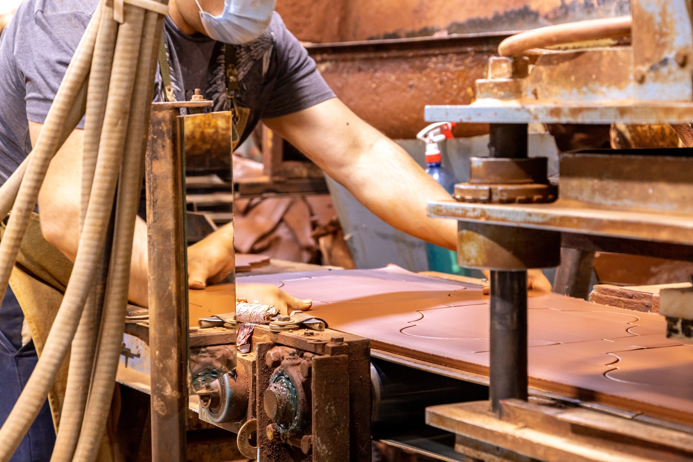 A maker feeding a sheet of clay through the tile press