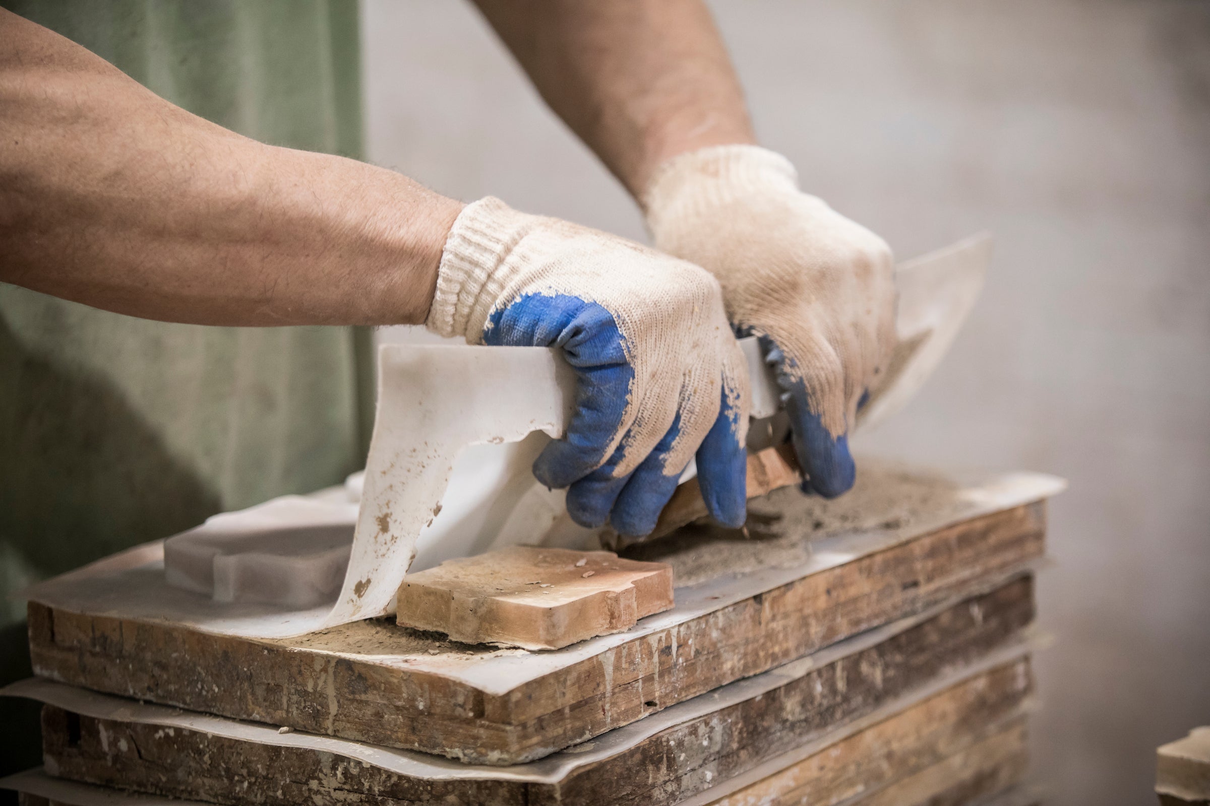 Gloved hands pulling a concrete tile from its mold