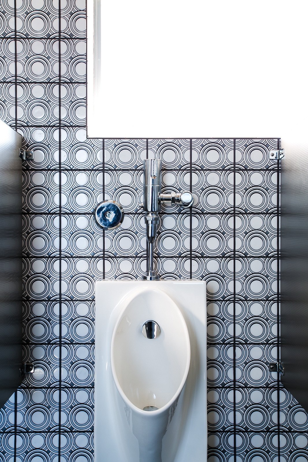 Rings tile behind the urinal