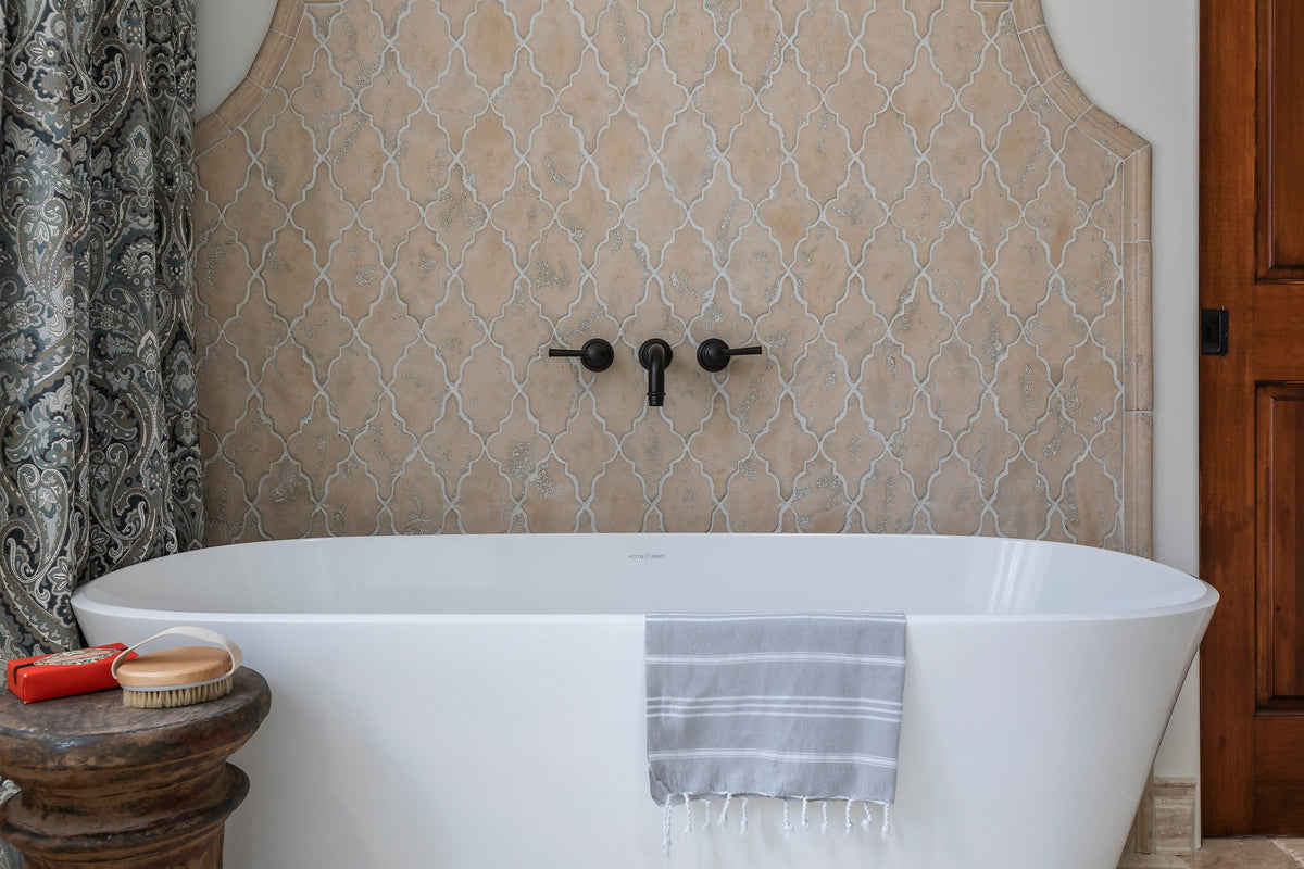 Freestanding tub before arched tile wall